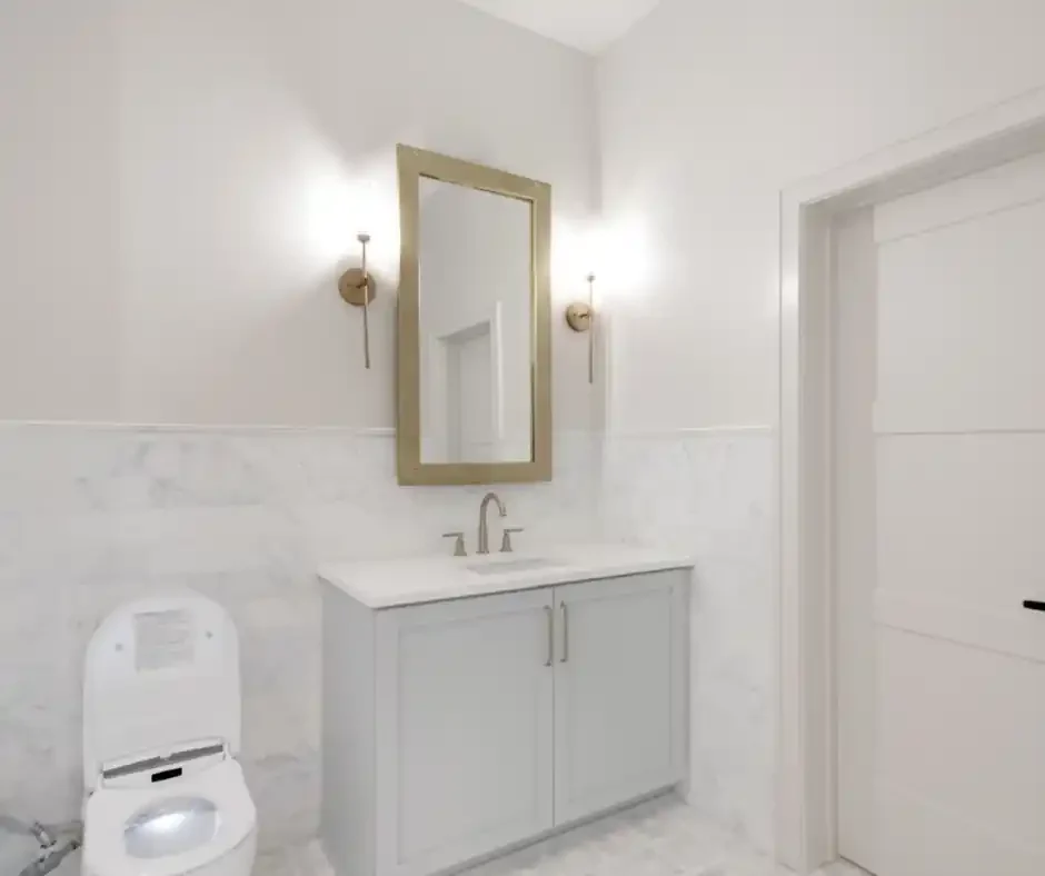 Custom bathroom vanity with a stone top, gold mirror and marble tile