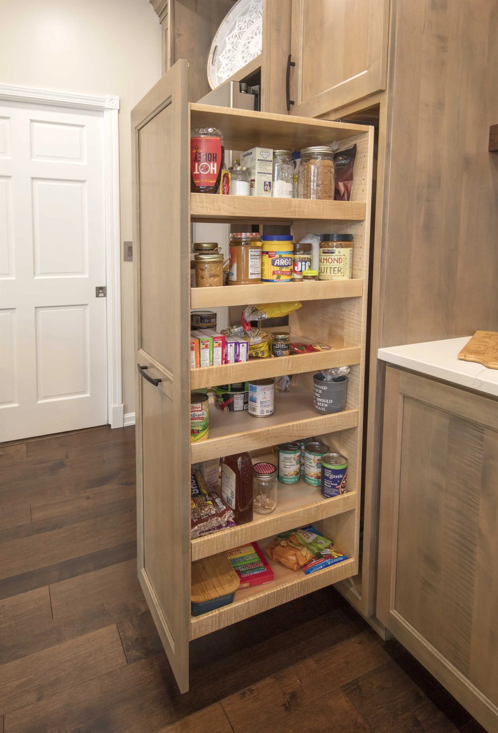 Pull-out pantry storage built into a custom maple cabinet